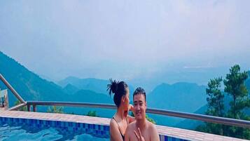 Una pareja en una piscina con un paisaje montañoso al fondo.