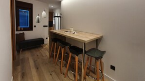 A modern kitchen with a wooden countertop, four bar stools, and pendant lights.
