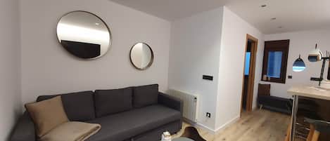 A modern living room with a dark grey sofa, a round coffee table, and a black rug.
