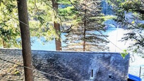 Una casa di legno con tetto spiovente, un portico con ringhiere e vista sull'acqua.