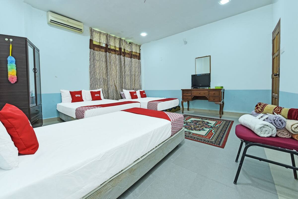 A hotel room with two beds, a desk, a TV, and a wardrobe.