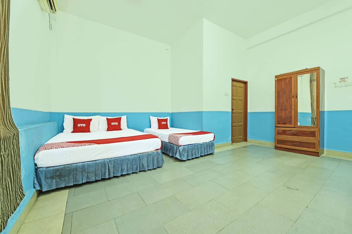 A hotel room with two beds, a wardrobe, and a door.