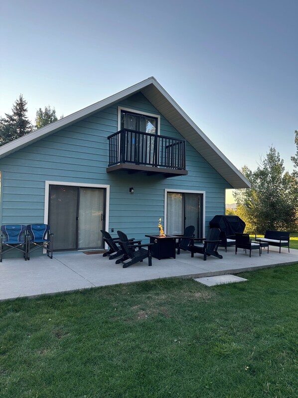 Un bâtiment à deux étages doté d’un balcon, d’un espace extérieur aménagé pour s’asseoir et d’un barbecue.