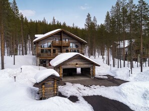 En hytte med veranda, garage og snefyldt indkørsel.