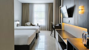 A hotel room with two beds, a desk, a chair, a TV, and a window with curtains. - Rylich Panorama Hotel (Sorong)