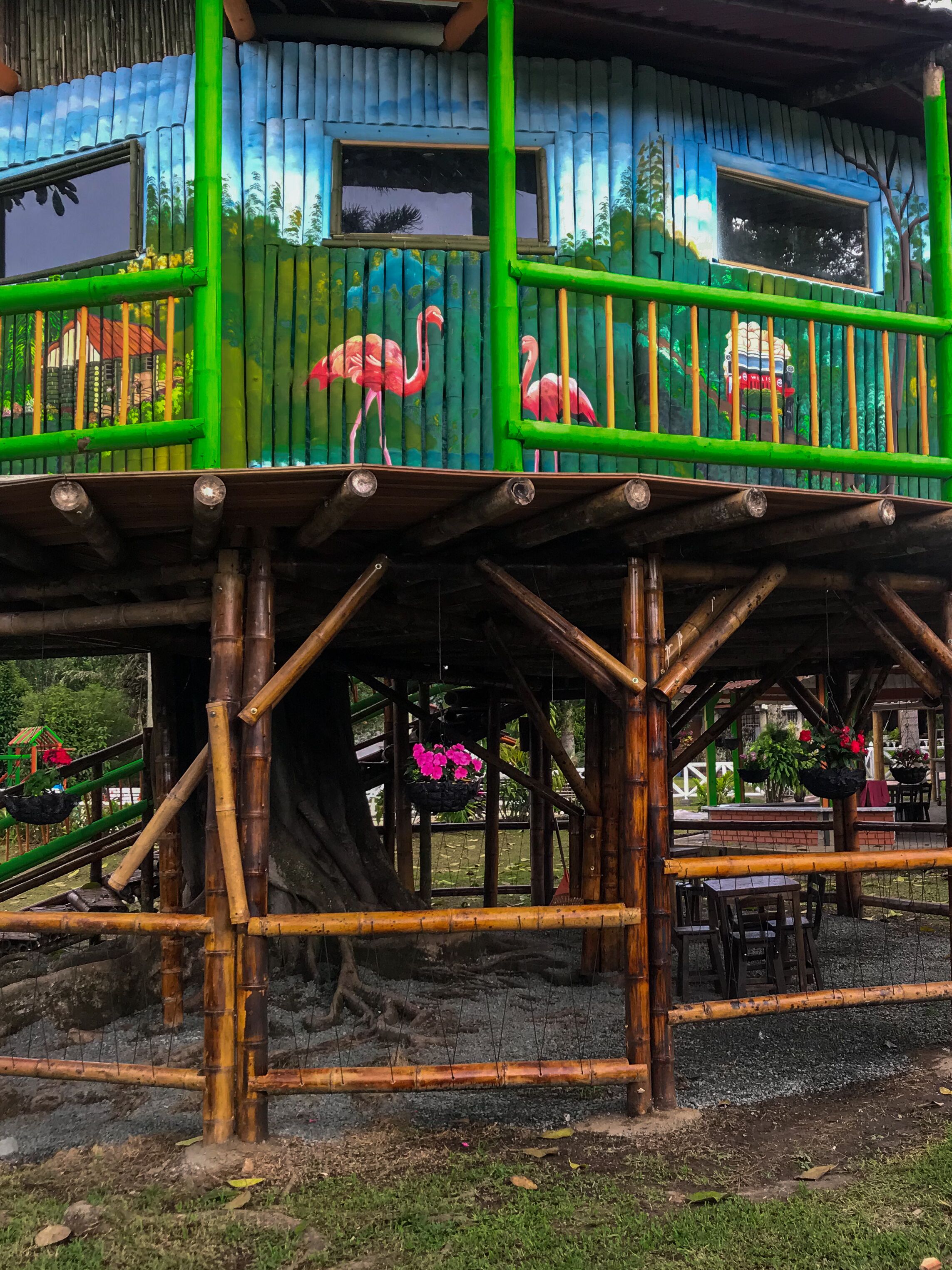 A multi-level wooden structure with balconies, a slide, and hanging flower baskets.