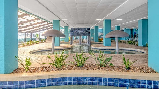 Eine Hotelhalle mit einer zentralen Fontäne, Fliesenböden und teal-farbenen Wänden.