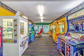 An arcade with various gaming machines, a patterned floor, and a green wall.