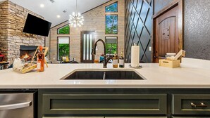 A modern kitchen with a stone accent wall, a built-in TV, and a large window.