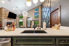 A modern kitchen with a stone accent wall, a built-in TV, and a large window.
