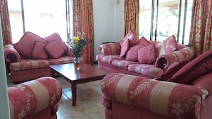 A living room with two sofas, a coffee table, and a vase with flowers. - Family size of 6 persons,  extra bed upon requestor , Beach front (Anse Boileau)