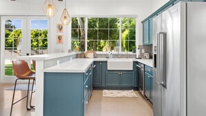A modern kitchen with teal cabinets, a stainless steel refrigerator, and pendant lighting. - Walkable Historic Phoenix Casita + Private Pool (Phoenix)