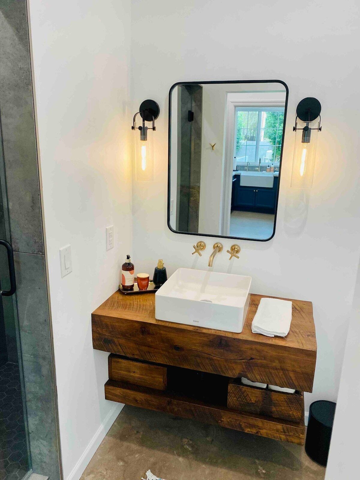 Une salle de bain avec un meuble-lavabo blanc, un grand miroir et deux appliques murales.