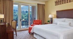 Relax in this serene space with a large bed, desk, and balcony offering a view of the outdoors.