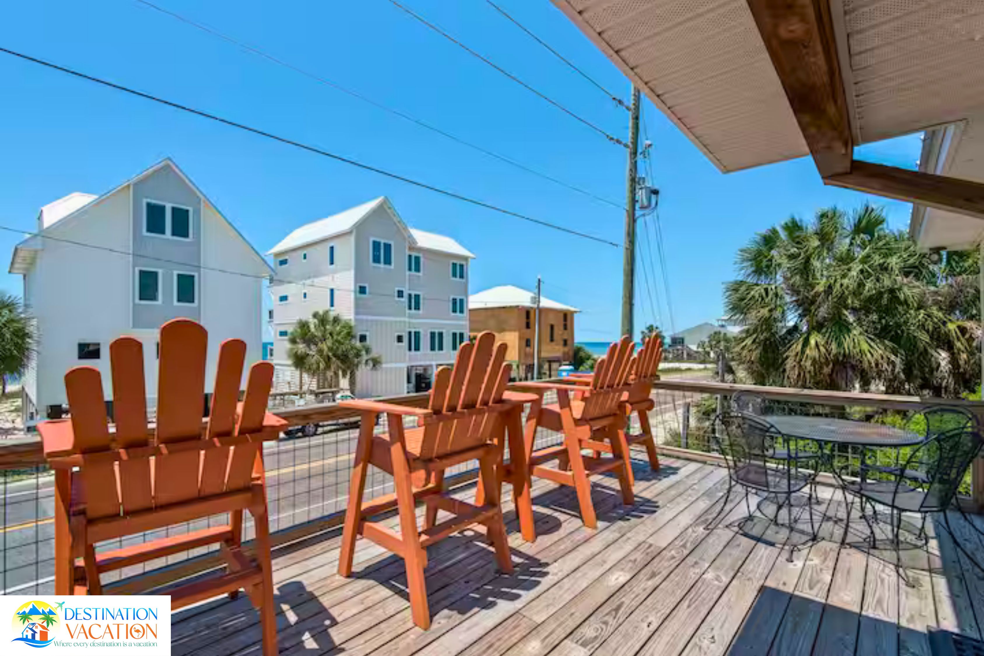 A wooden deck with outdoor seating and a view of a coastal area with buildings.