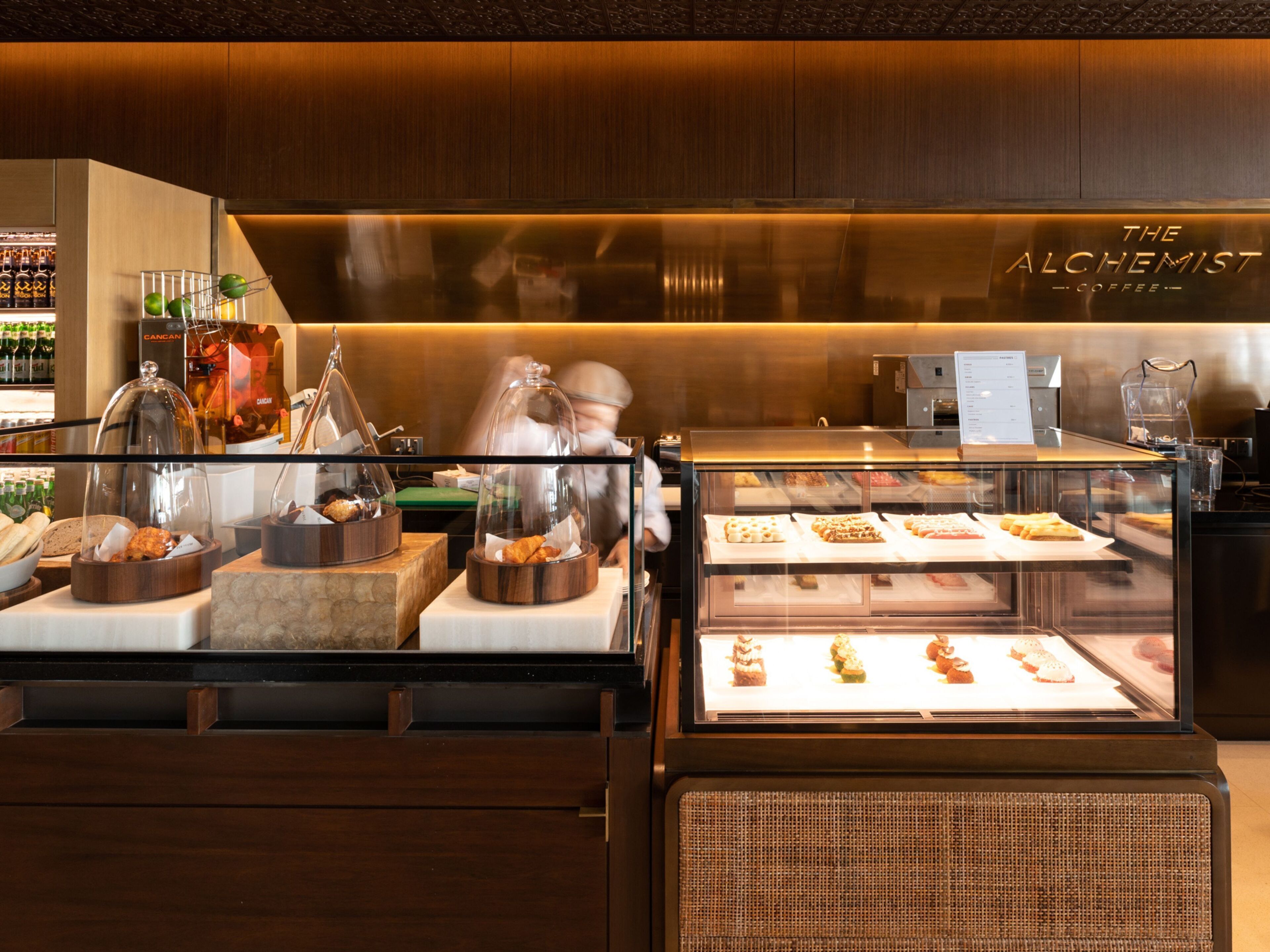 A coffee shop interior with a display case of pastries and a counter with coffee-making equipment.