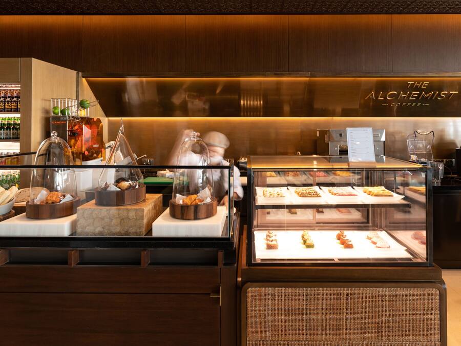 A coffee shop interior with a display case of pastries and a counter with coffee-making equipment.