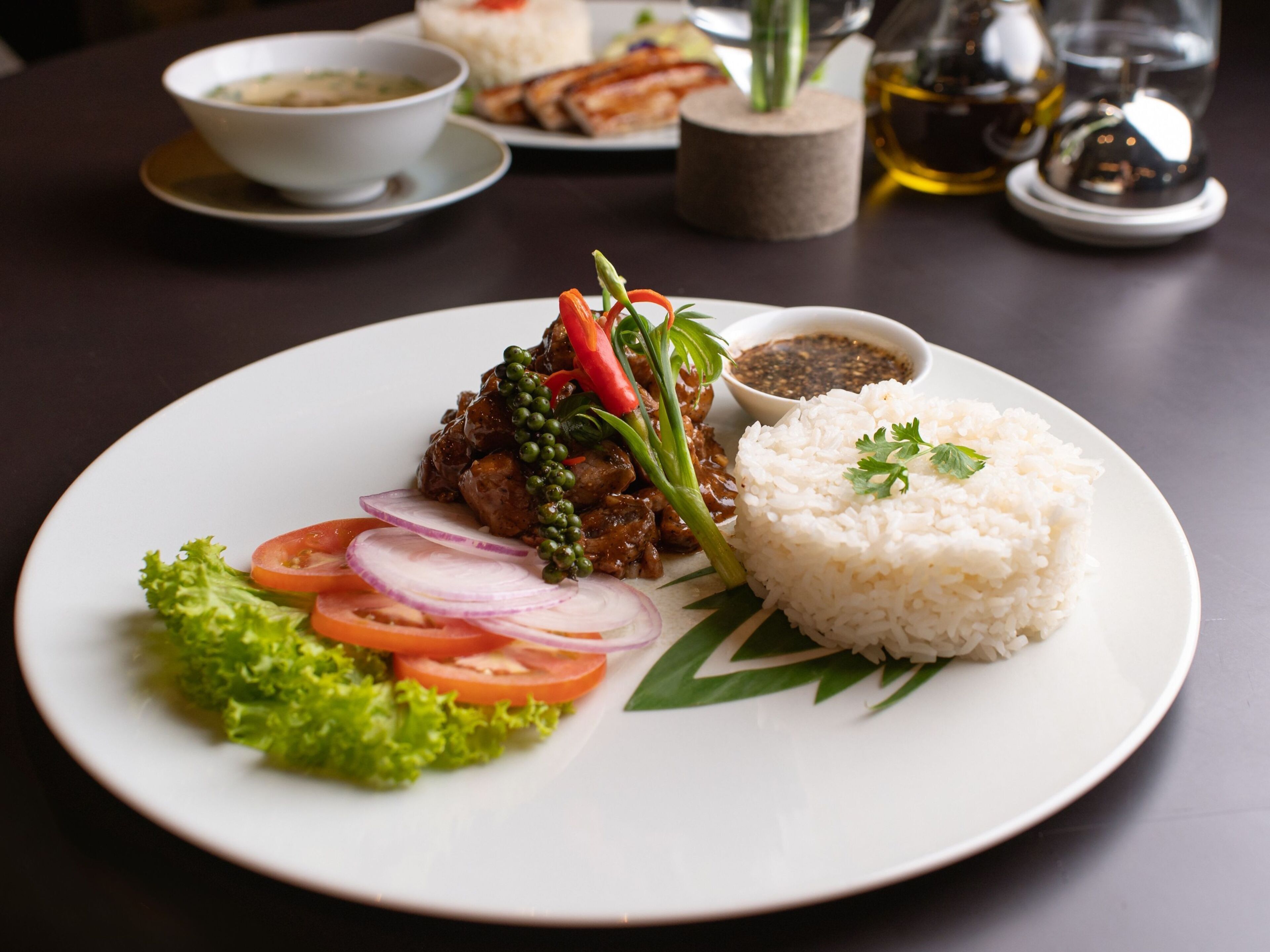 Un plato de comida con arroz, carne, verduras y un acompañamiento.