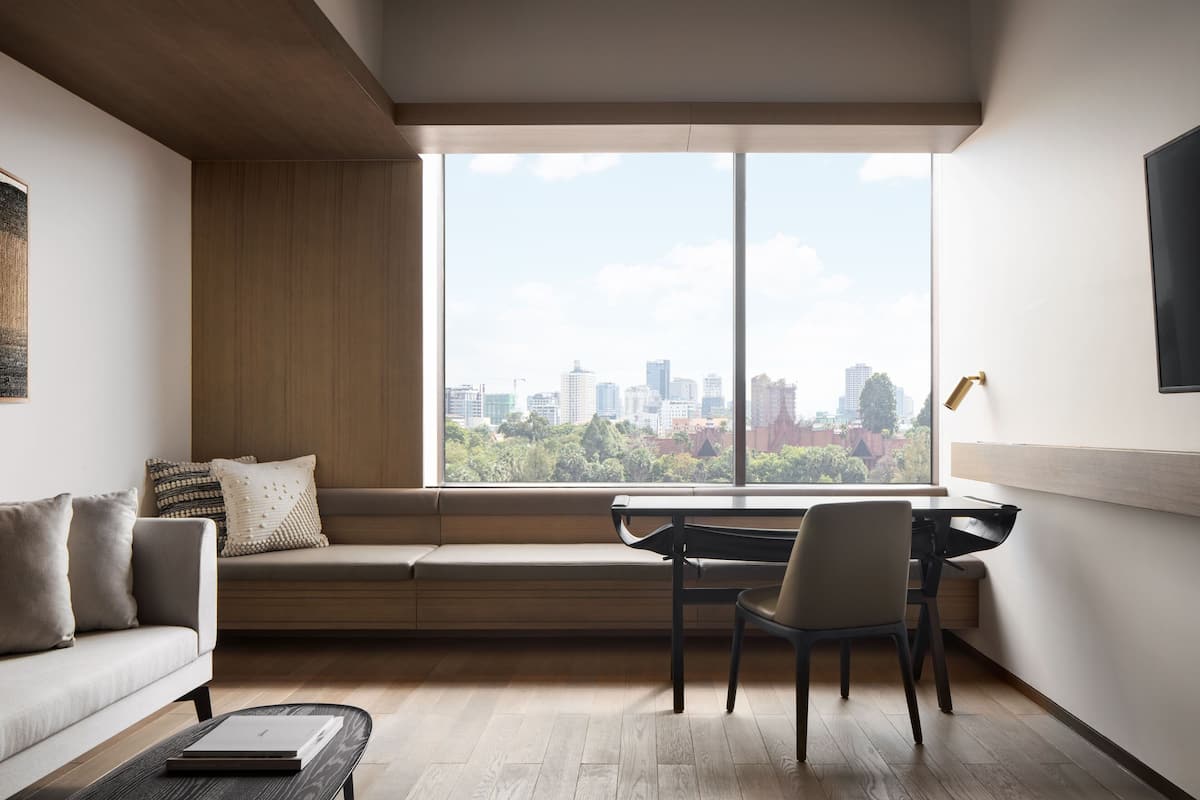 Ein modernes Wohnzimmer mit Stadtblick, einer Couch, einem Schreibtisch und einem Sessel.