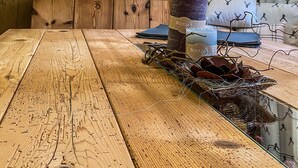 Een houten eettafel met een schilderij van bergen, kaarsen en decoratieve takken.