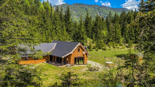 Een chalet met een ruim terras en uitzicht op een bebost berglandschap.