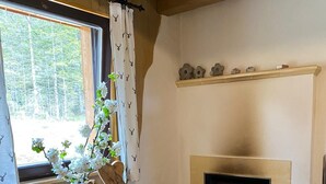 Een gezellige kamer met een open haard, houten meubels en een raam met gordijnen.
