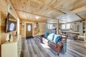 Indbydende kabineinteriør med træloft, en brun lædersofa, et tekøkken og et spisebord.