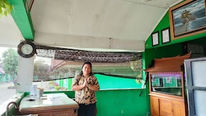A room with a green wall, a wooden cabinet, a clock, and a framed picture. - Hotel Bukit Sentabi Penembahen (Medan)