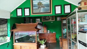 A room with a green wall, wooden furniture, a fish tank, and a refrigerator. - Hotel Bukit Sentabi Penembahen (Medan)