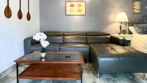 A modern living room with a leather sofa, a glass coffee table, and a framed picture on the wall.