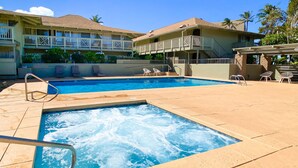A swimming pool with a hot tub, lounge chairs, and a covered area with a pergola.