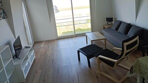 A modern living room with a sofa, a coffee table, a TV, and a sliding glass door to a balcony.