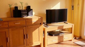 Ein Holzunterhaltungsschrank mit einem Flachbildfernseher, einer Musikanlage und einem Laptop.
