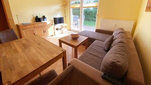 Ein gemütliches Wohnzimmer mit einem Holzesstisch, einer Couch und einem Fernseher.