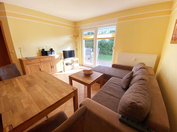 A cozy living room with a wooden dining table, a sofa, and a television.