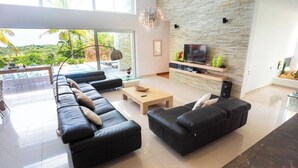 Un salon moderne avec un canapé en cuir noir, une table basse en bois et un mur décoratif en pierre.