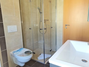 A bathroom with a glass-enclosed shower, a white toilet, and a white bathtub.
