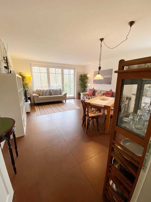 Un grand espace de vie comprenant un canapé, une table à manger et des chaises. Il y a également une cuisine équipée d’un réfrigérateur et de placards.