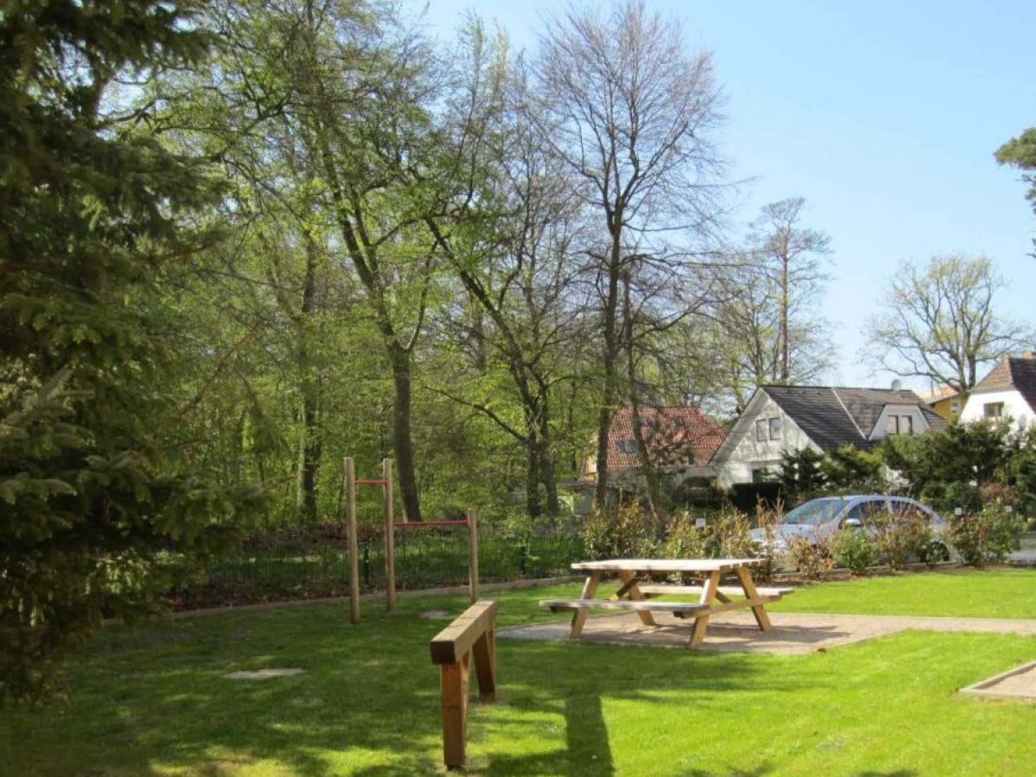 A park with a wooden swing set, picnic tables, and a bench.