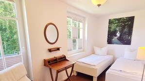 A room with two beds, a desk, a chair, and a window with blinds. - Vacation apartment Bucheneck 15 (Graal-Müritz)