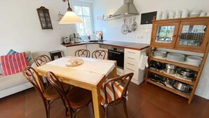 A compact kitchen with a dining table, chairs, a built-in oven, and a cabinet with dishes. - Vacation apartment Bucheneck 15 (Graal-Müritz)