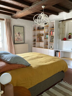 A bedroom with a bed, a bookshelf, a radiator, and a ceiling light fixture.