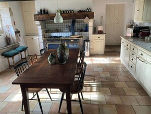 A kitchen with a wooden table, chairs, a tiled backsplash, and a stove.