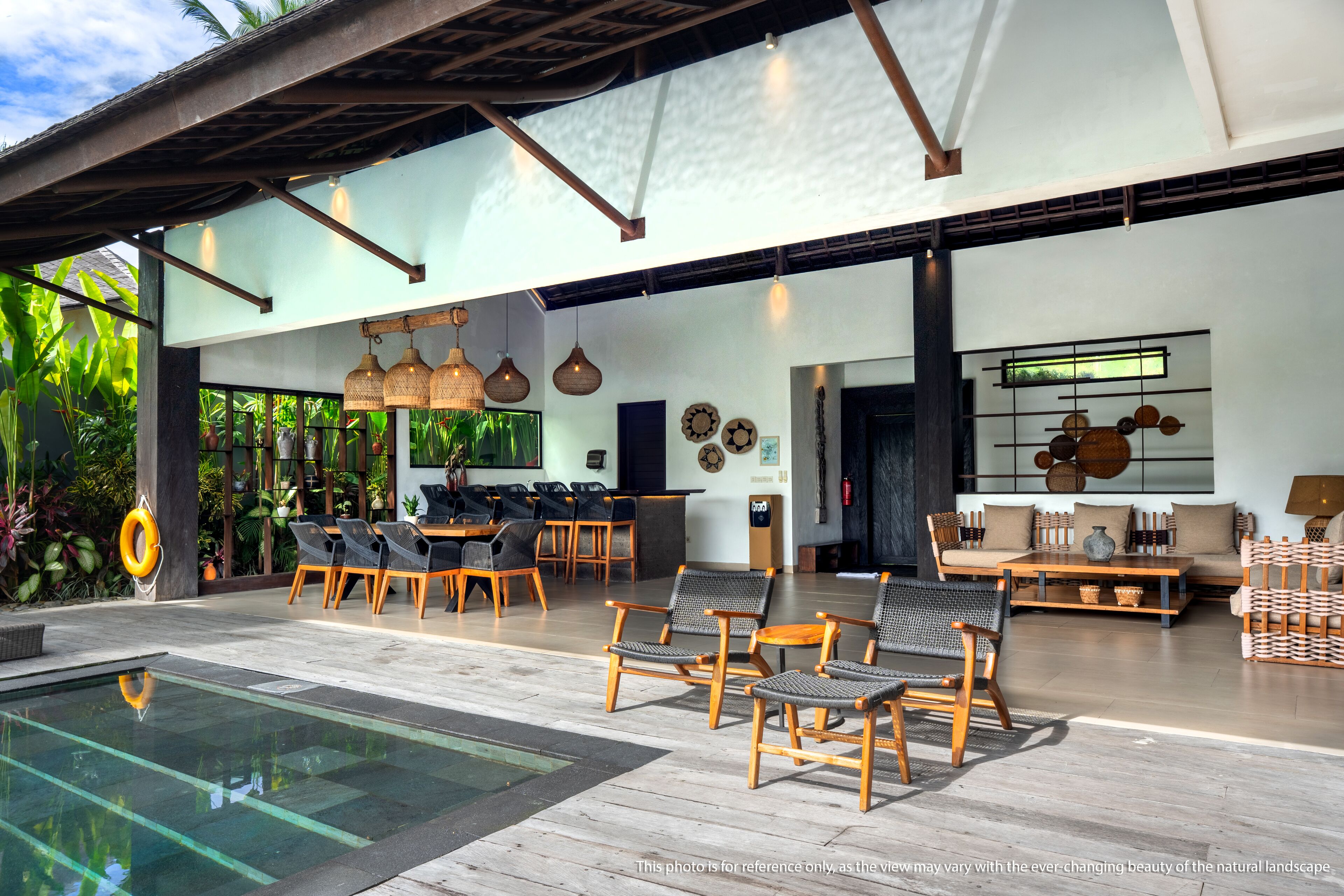 A modern outdoor lounge area with a pool, wooden furniture, and a view of lush greenery.