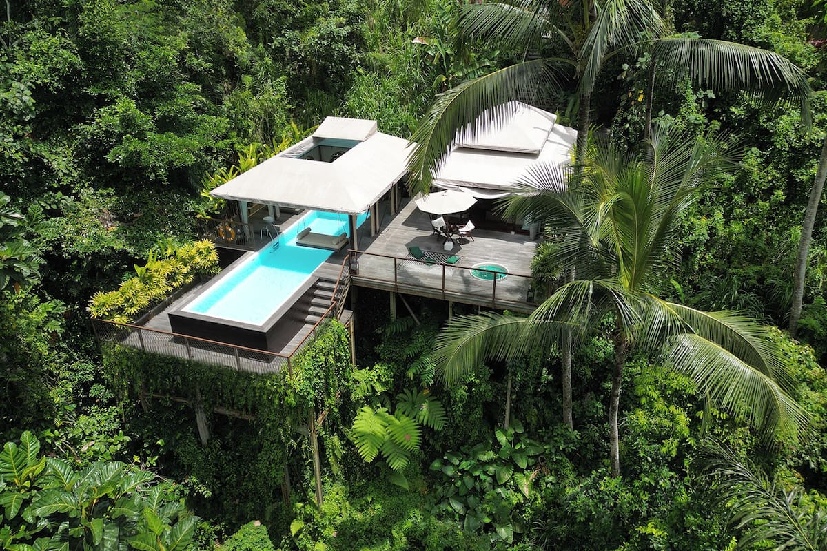 A private villa with a swimming pool, outdoor seating, and lush tropical surroundings.