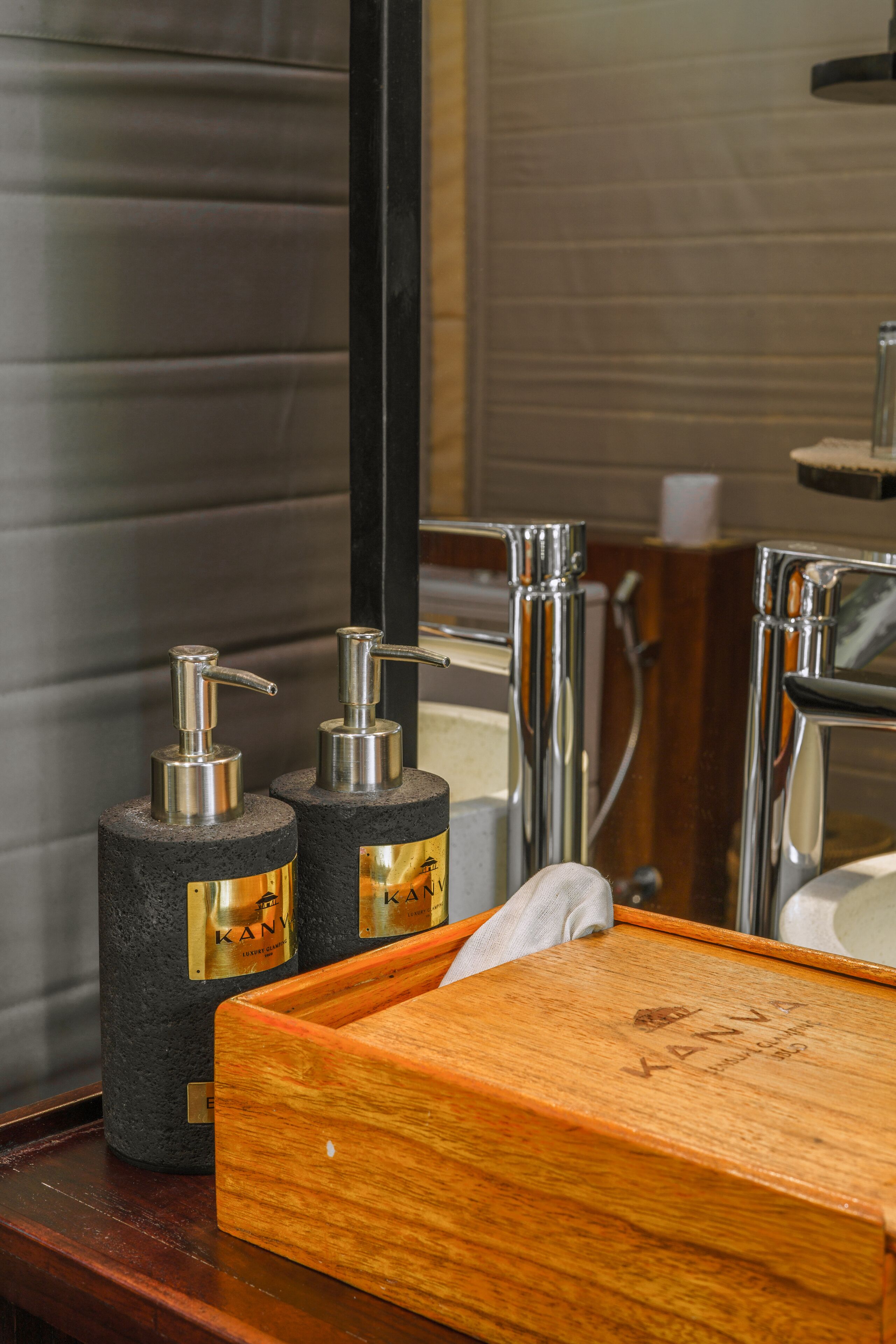 A bathroom with a wooden vanity, two black soap dispensers, and a mirror.