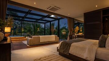 A modern bedroom with a large window, a bed, a sofa, and a desk area.