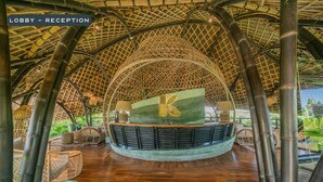 A lobby reception area with a bamboo ceiling, a reception desk, and wicker furniture. - KClub Ubud (Tegallalang)