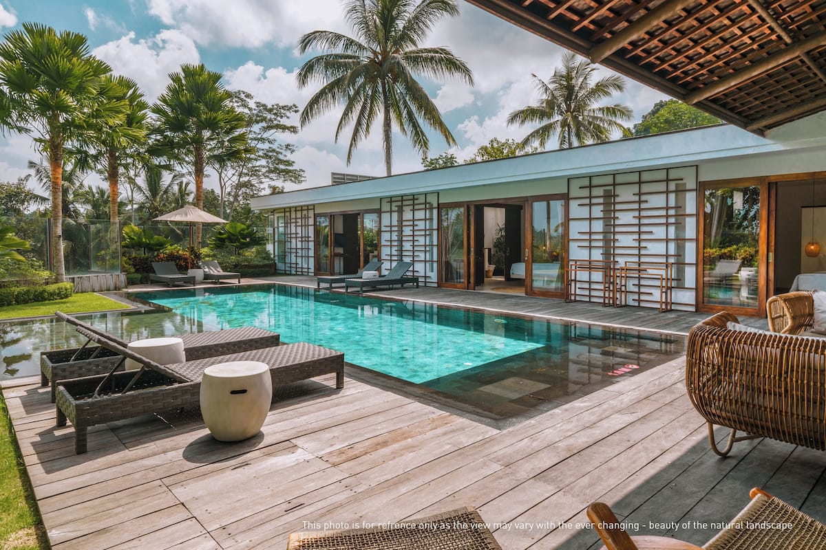 A modern pool area with lounge chairs, a wooden deck, and a glass-enclosed building.