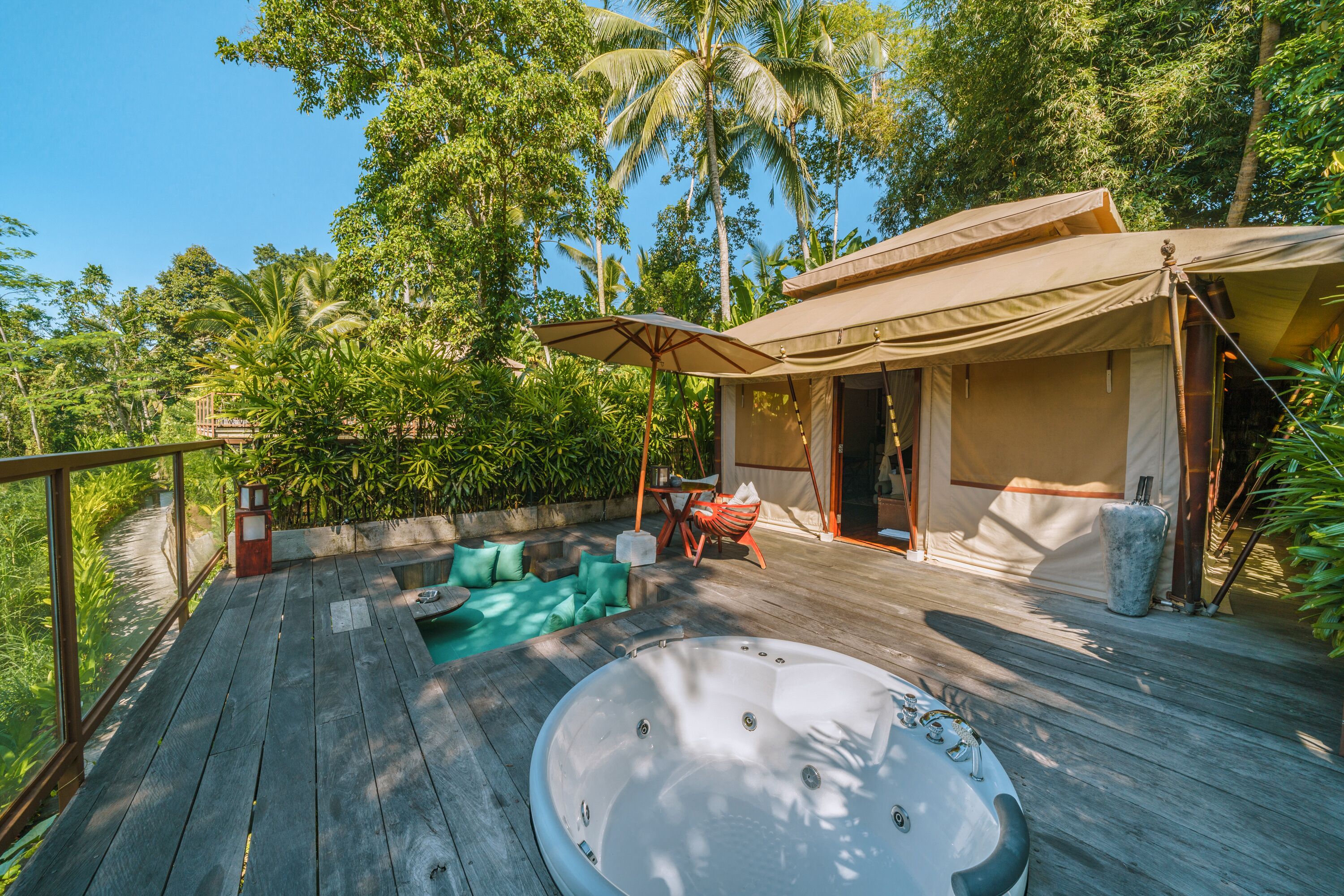 A wooden deck with a hot tub, outdoor seating, and a tented area.